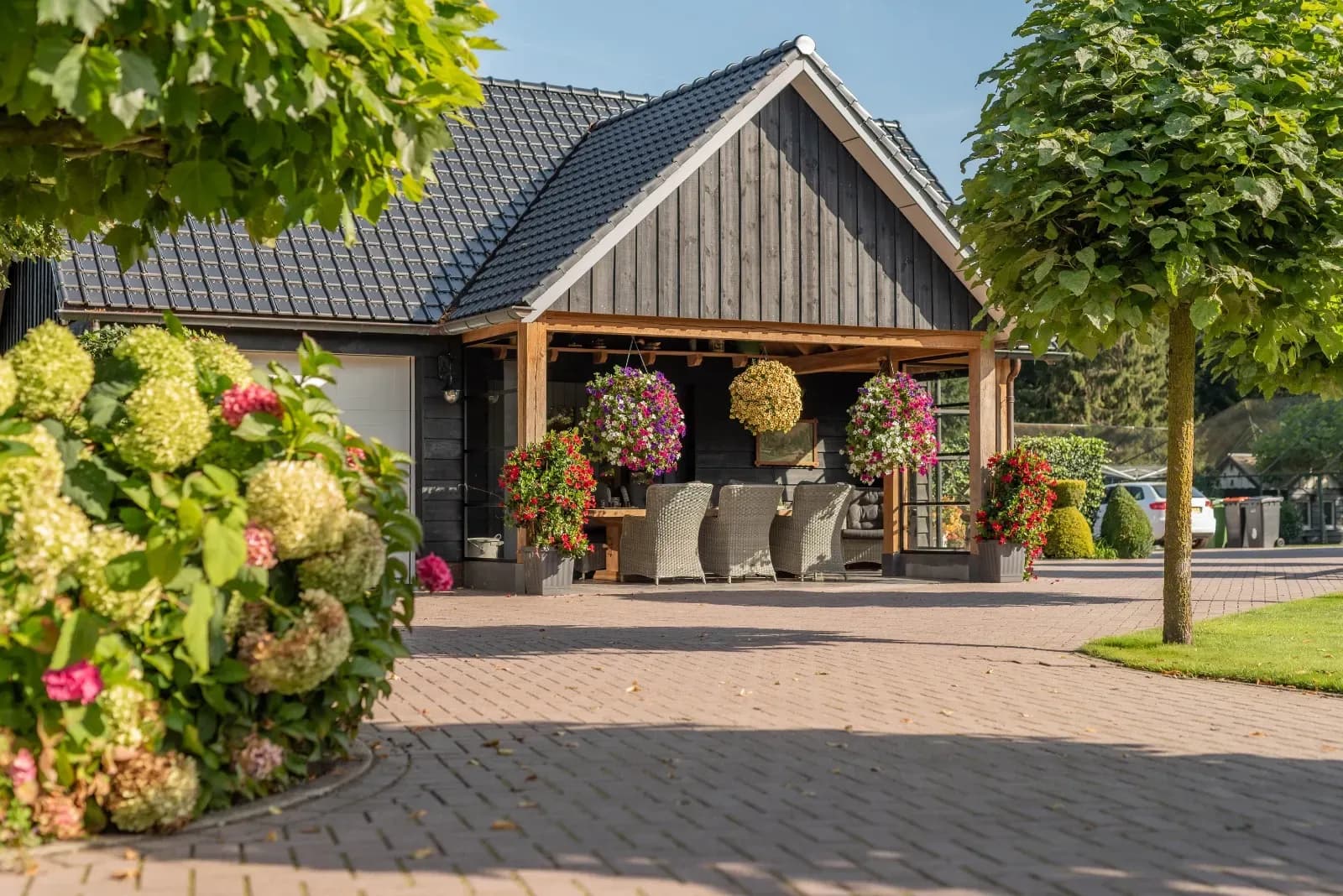 Schuur met overdekte veranda in zwart hout, met eiken draagconstructie en hortensia's