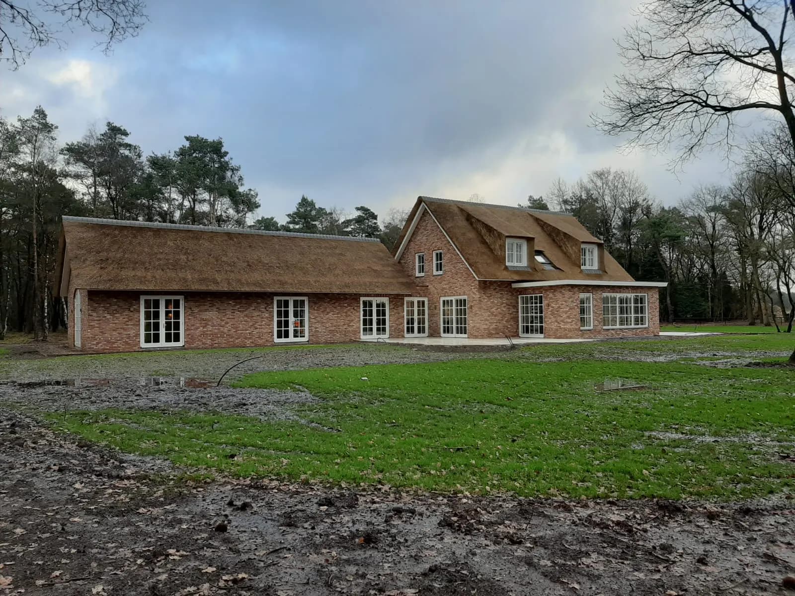 Nieuwbouw landhuis met rieten kap en handvormsteen, gelegen aan de bosrand