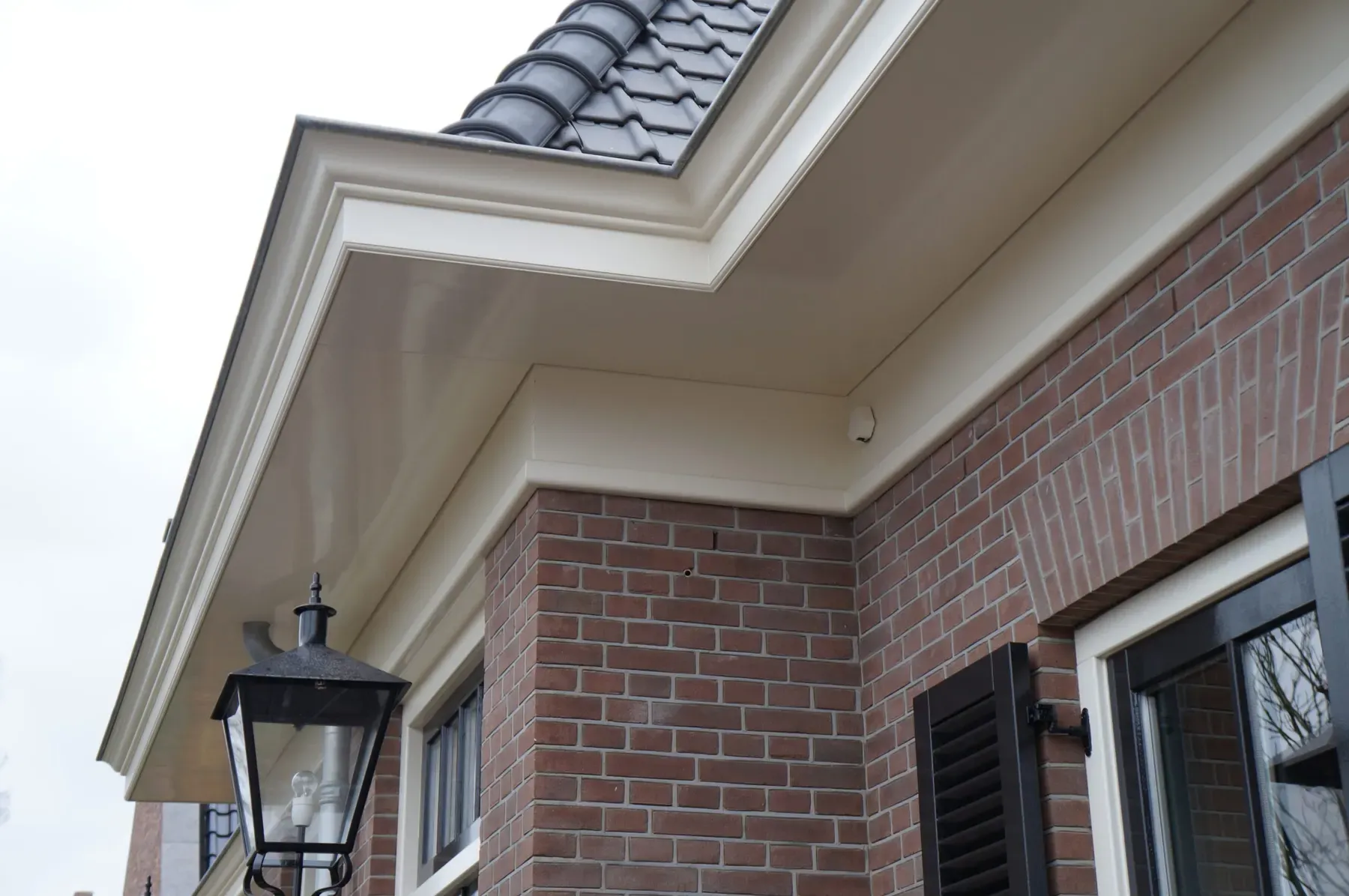 Klassieke woning in metselwerk met geprofileerde kroonlijst en buitenlamp